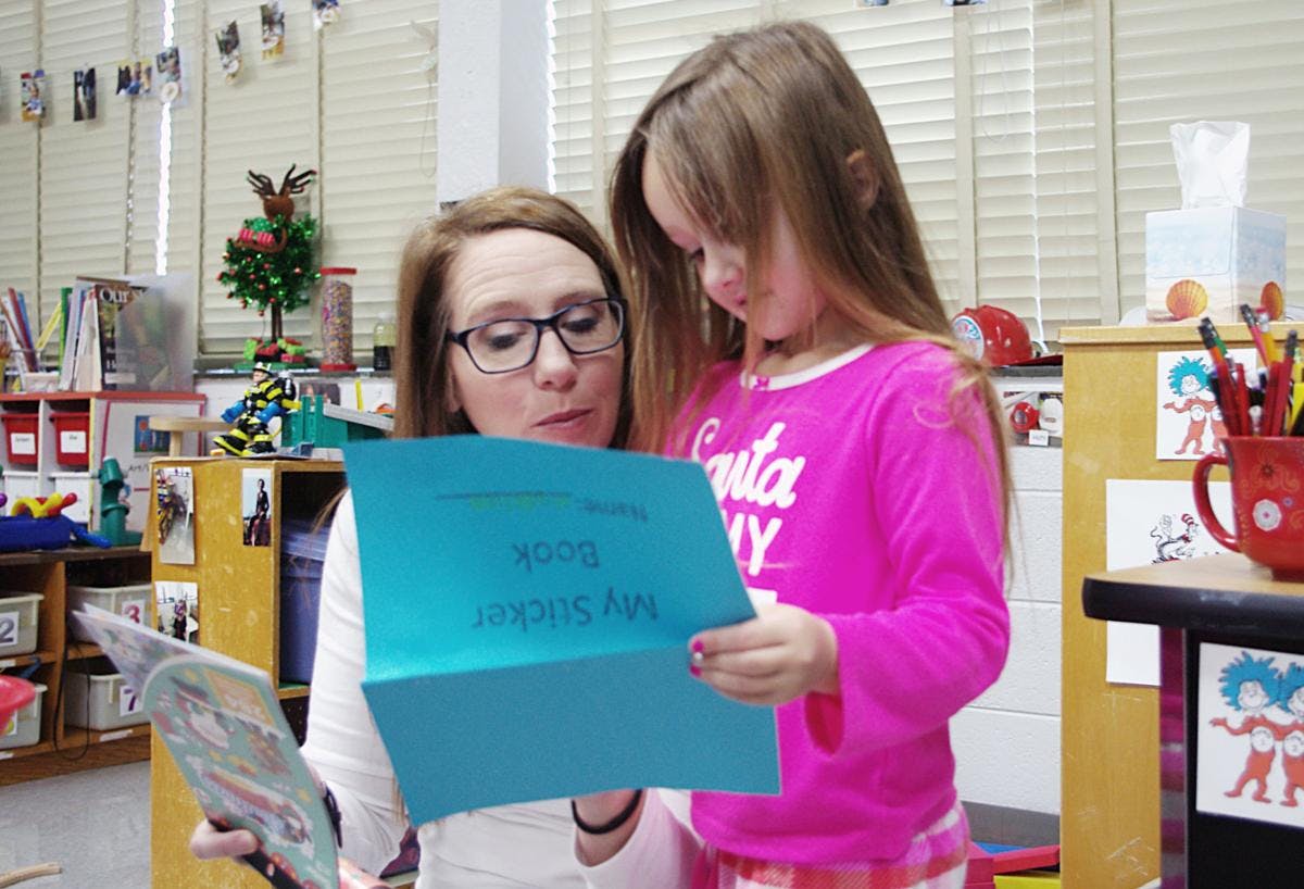 Person and child reading a blue paper together in a classroom