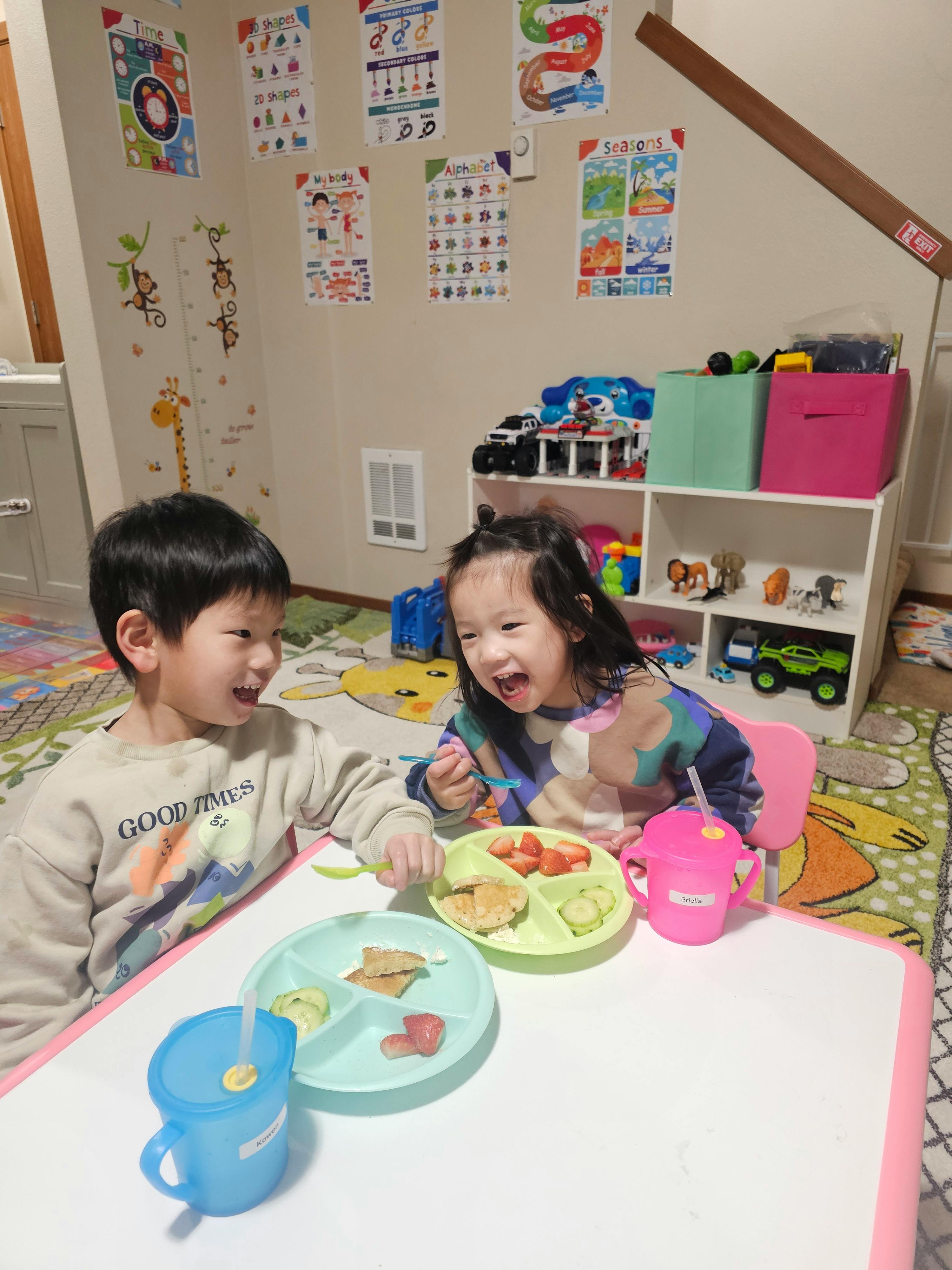 Two children eating at a table with divided plates
