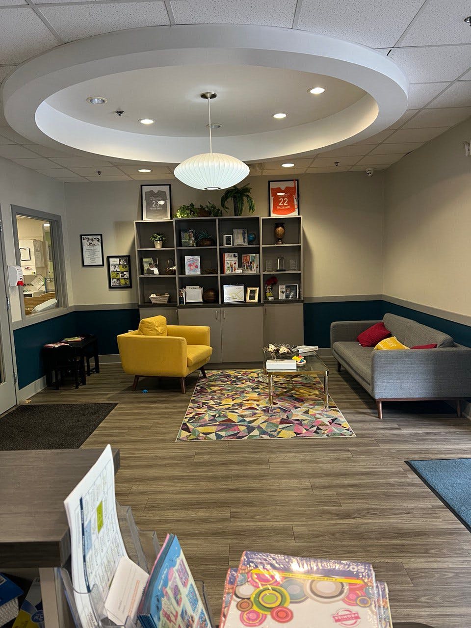 Waiting room with a yellow armchair, gray sofa, and bookshelf