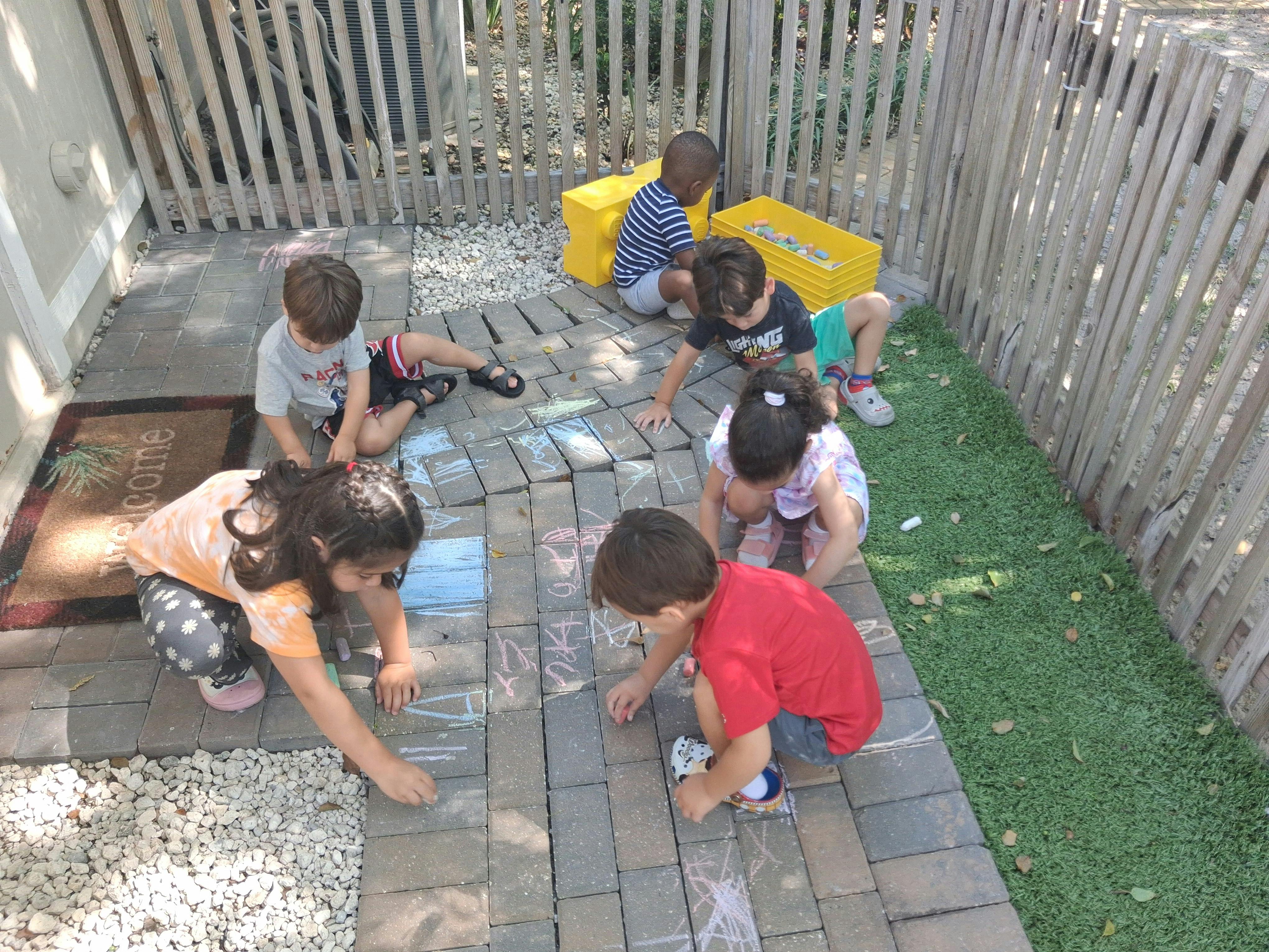 Group of children drawing with chalk on a paved patio