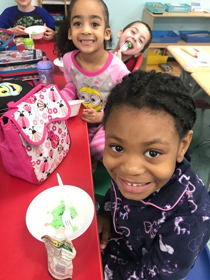 Three children at a table, two smiling at the camera
