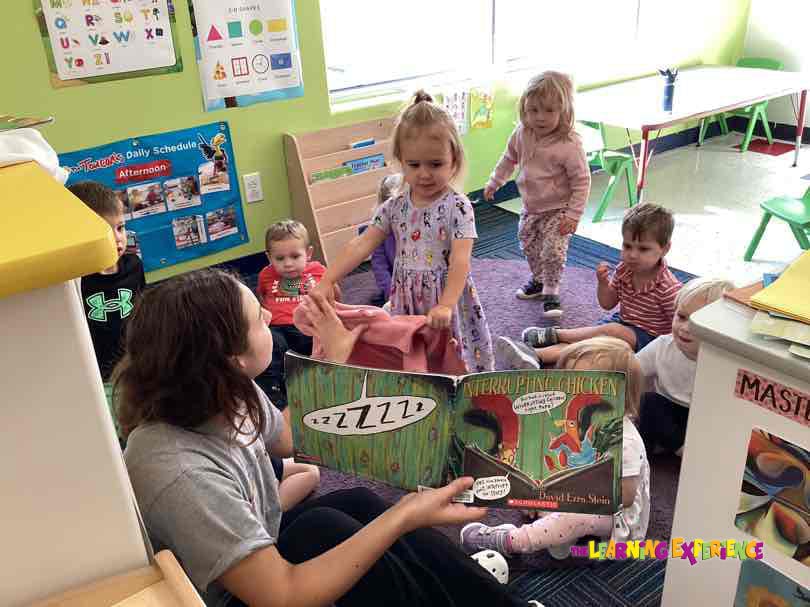 Adult reading a book to children in a classroom