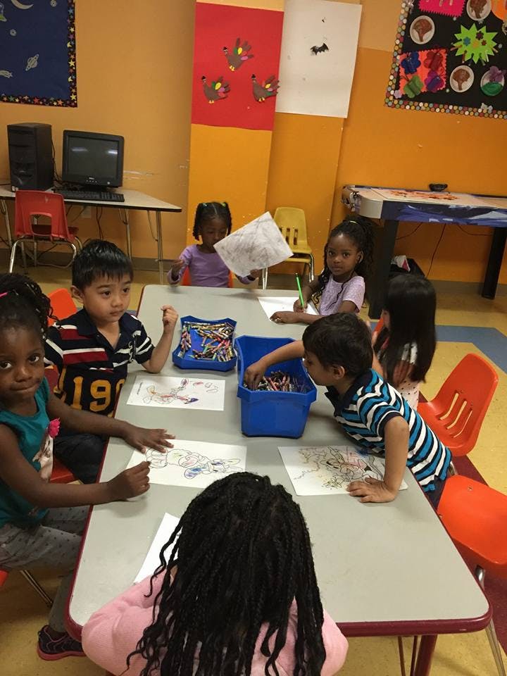 Children drawing and coloring at a table in a classroom