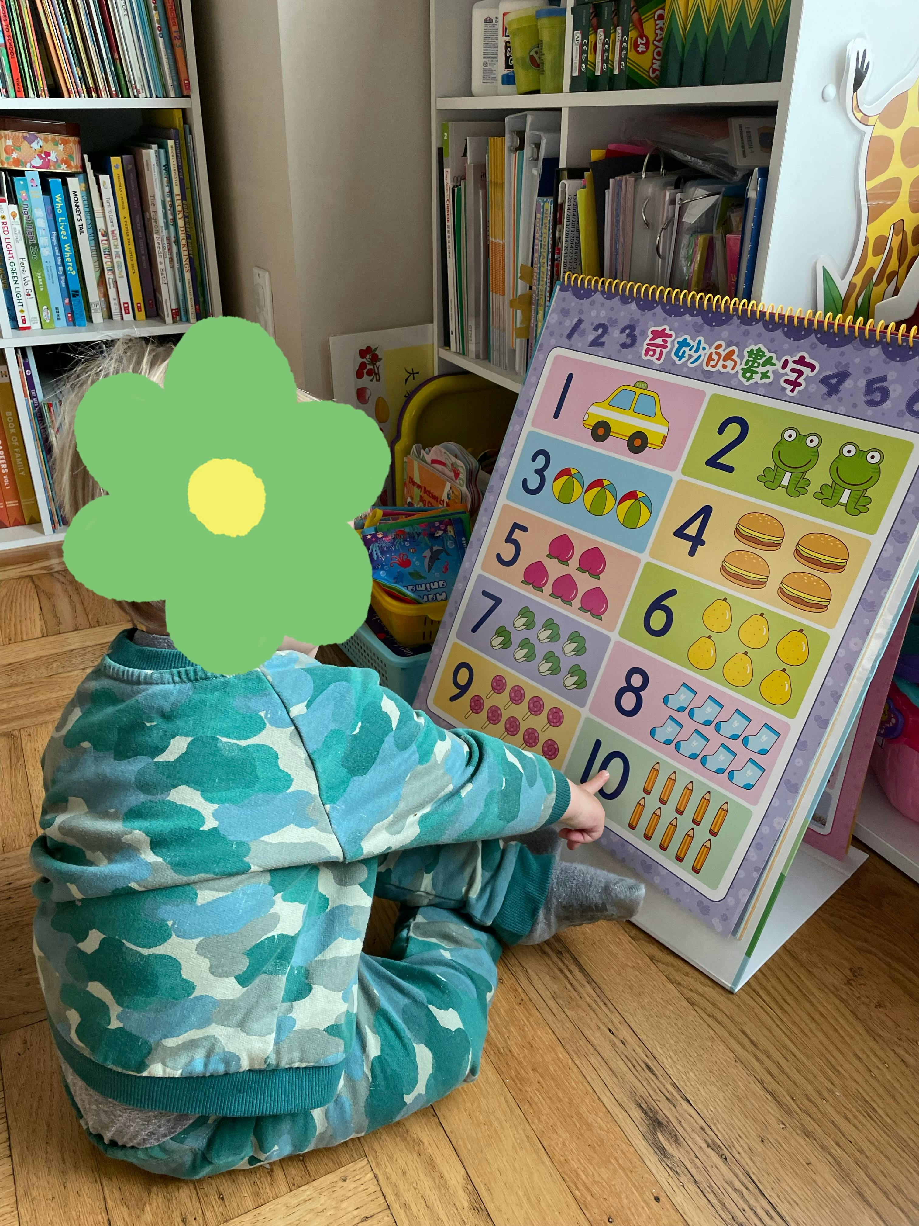 Child sitting on floor looking at a large number chart