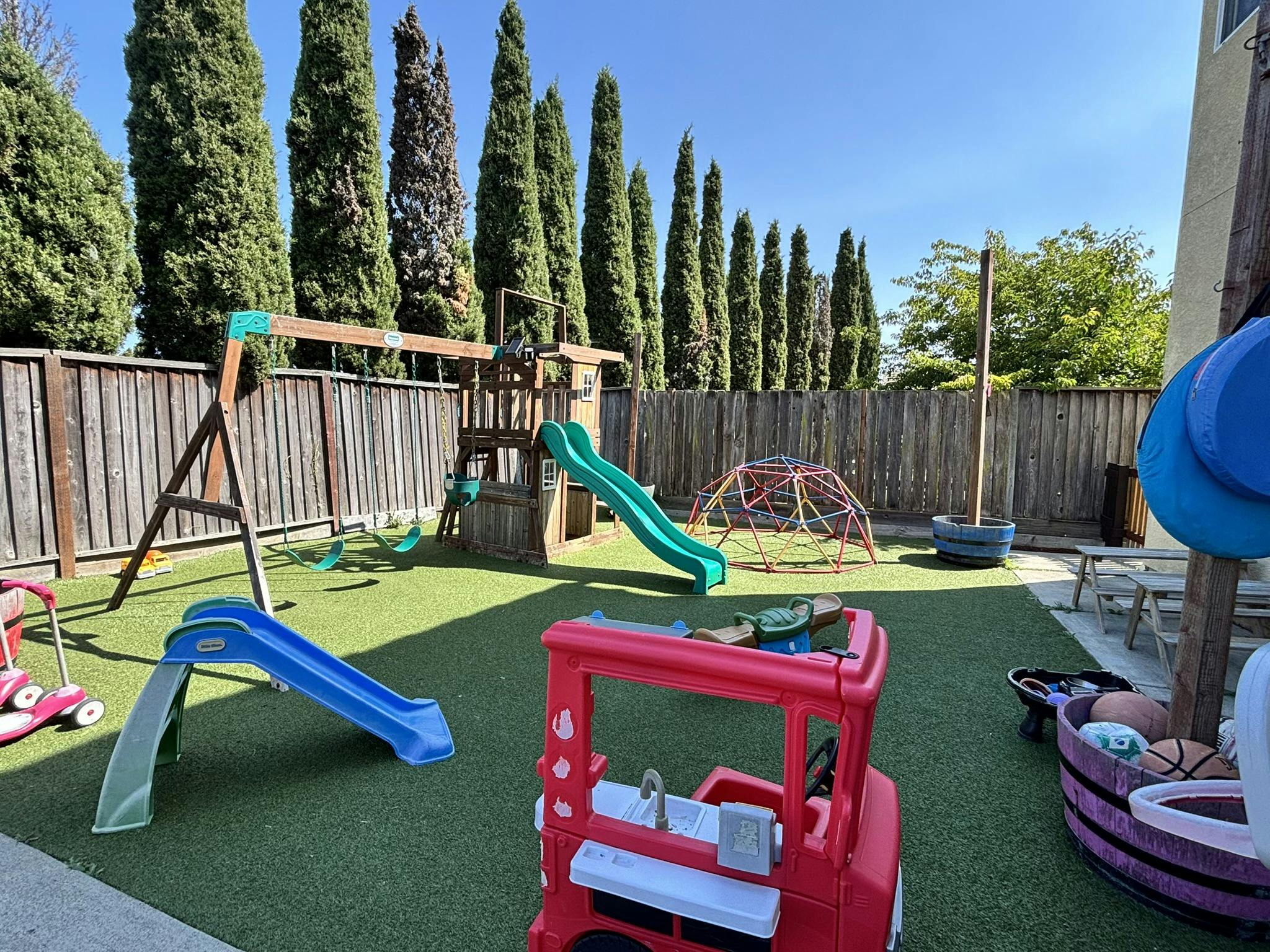 Outdoor playground with slides, swings, and climbing dome on artificial turf
