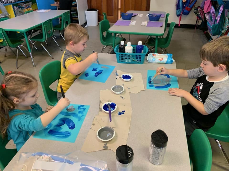 Three children painting at a table