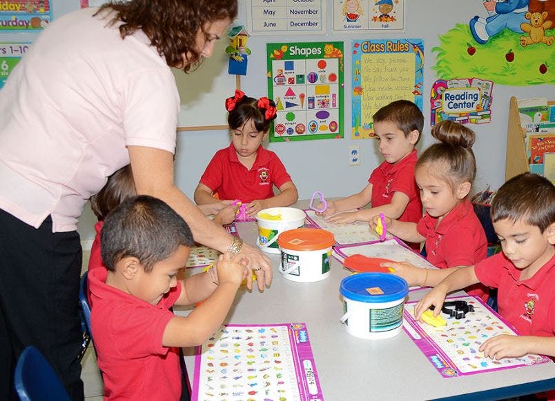 Adult helping children with an activity in a classroom