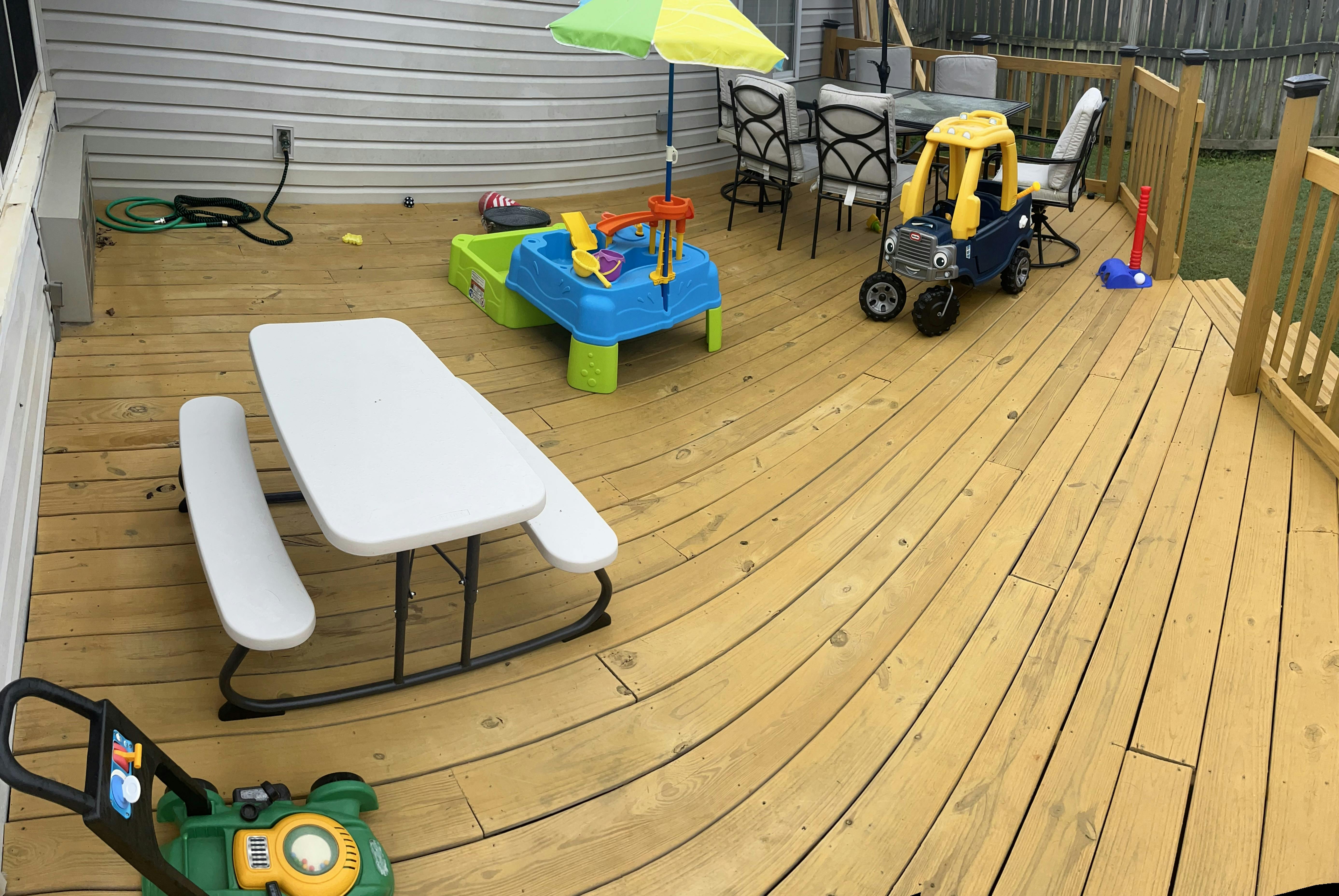 Wooden deck with a white picnic table and children's toys