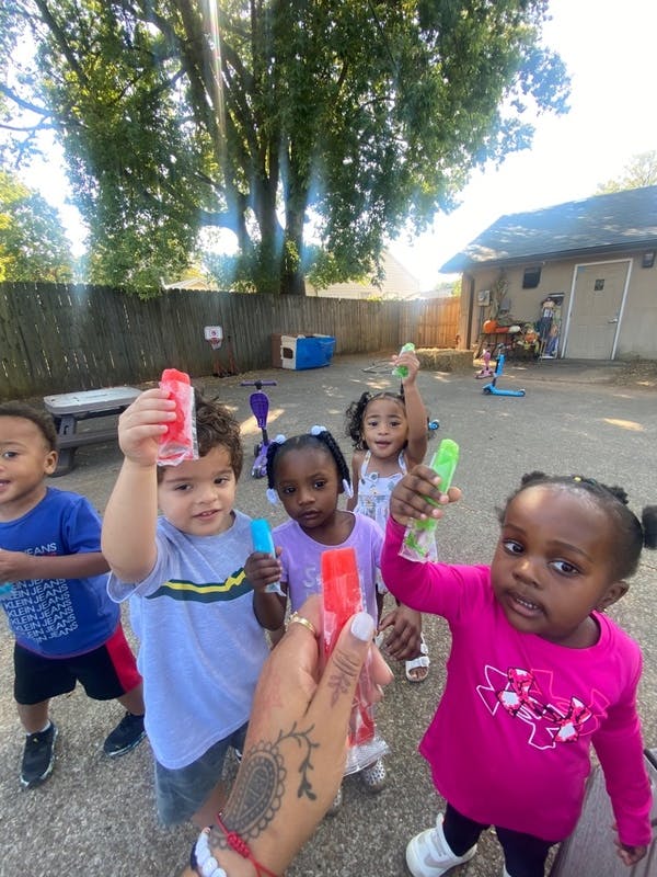Children holding ice pops on a playground