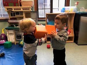 Two children holding orange blocks together