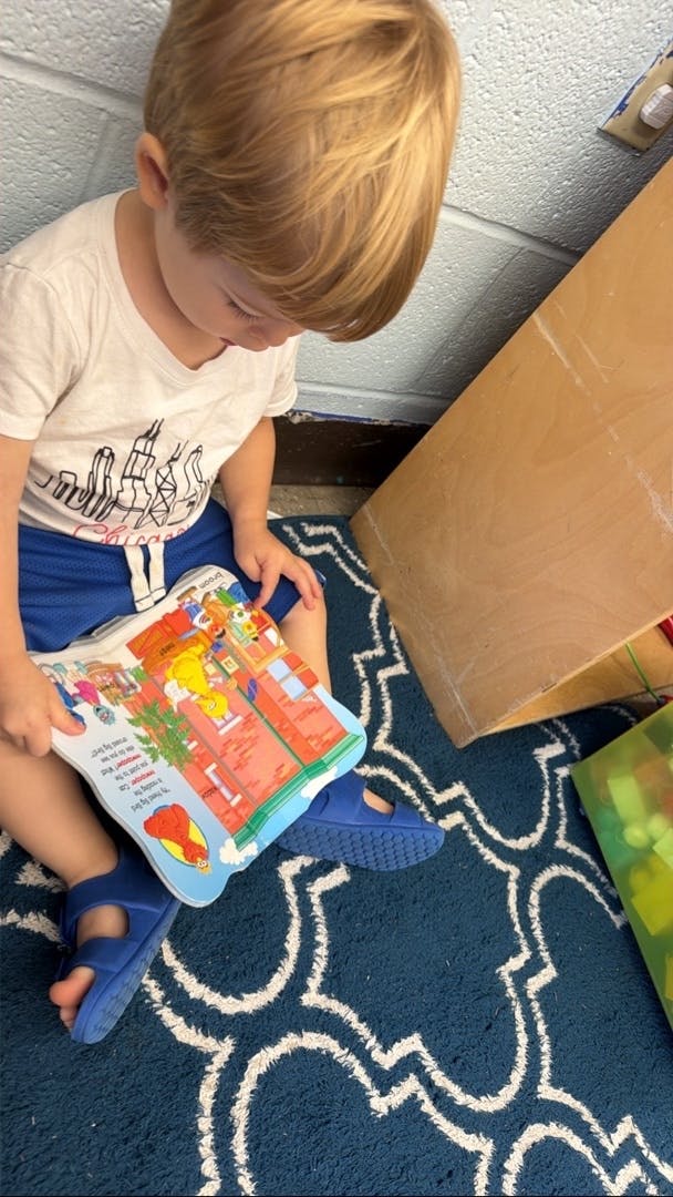 Child sitting on a rug reading a picture book