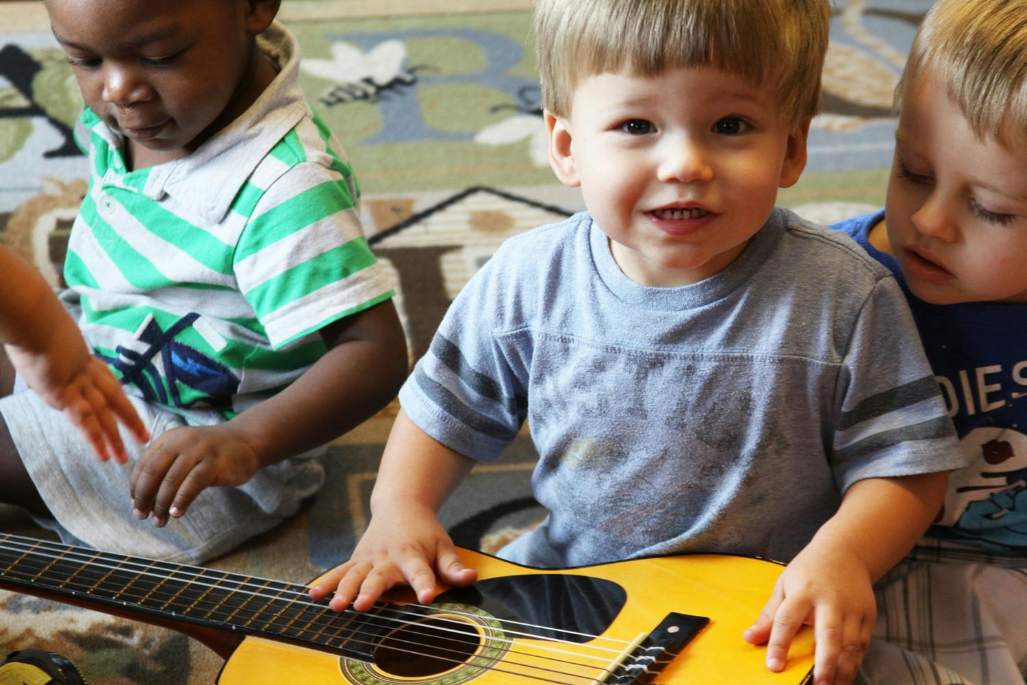 Three children playing with a guitar