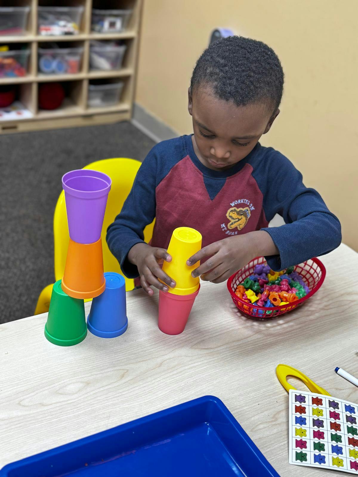 Child stacking colorful plastic cups on a table