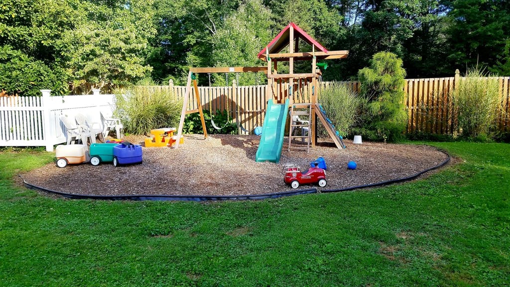 Backyard playground with swings, slide, and toy vehicles