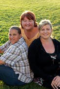 Three people sitting in grass
