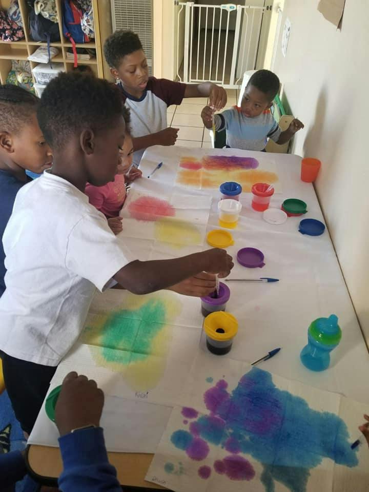 Children painting with colorful liquids at a table