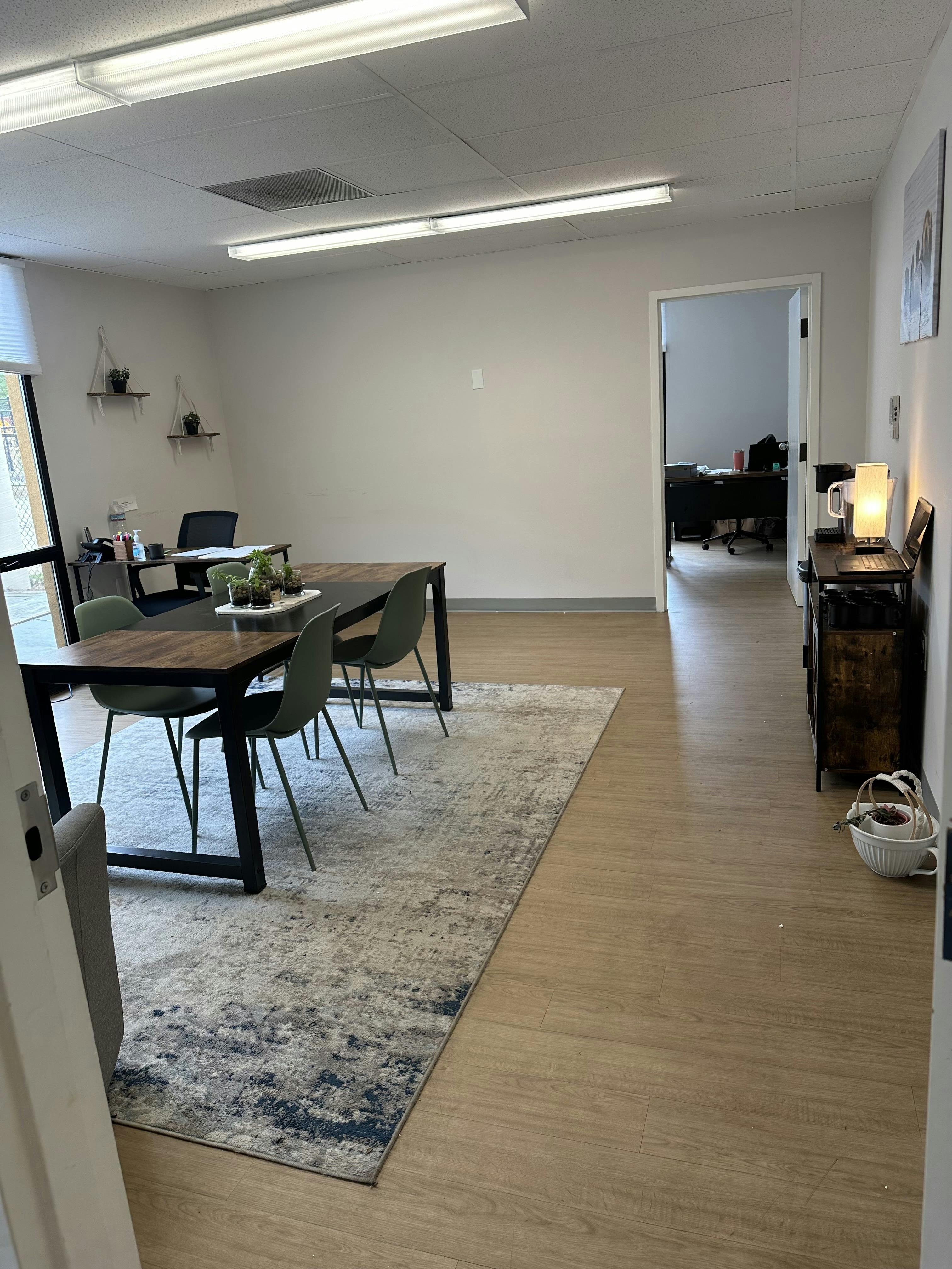 A conference room with a large table, chairs, and an adjacent office space