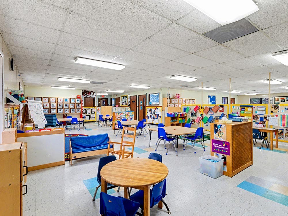 Empty classroom with small tables, chairs, and learning materials
