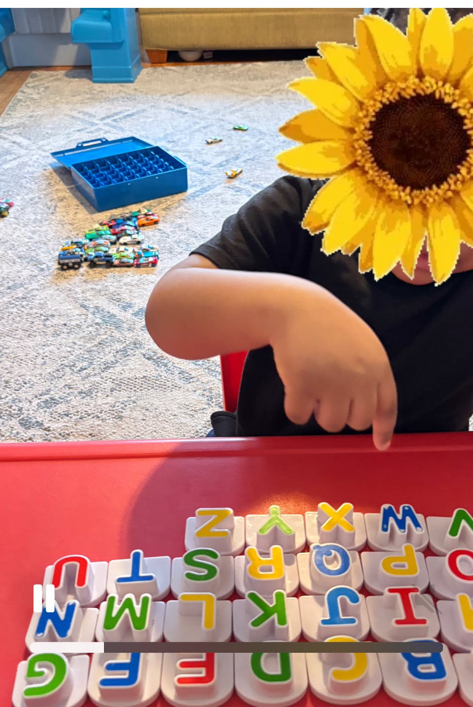 Child pointing at alphabet letter toys on a table
