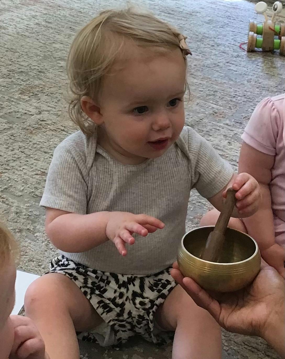 Child looking at a singing bowl held by a person
