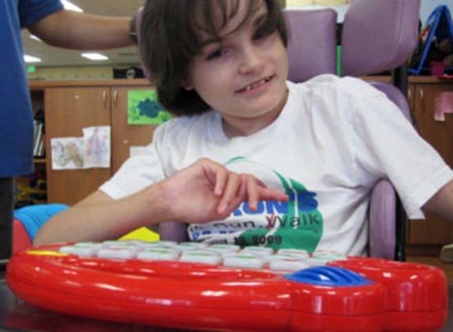 Child in a wheelchair interacting with a red toy
