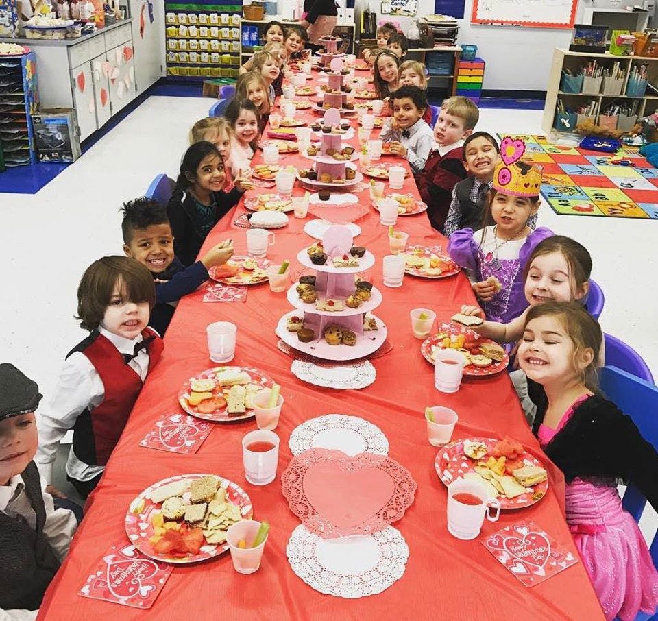 Children sitting at a long table with food and drinks