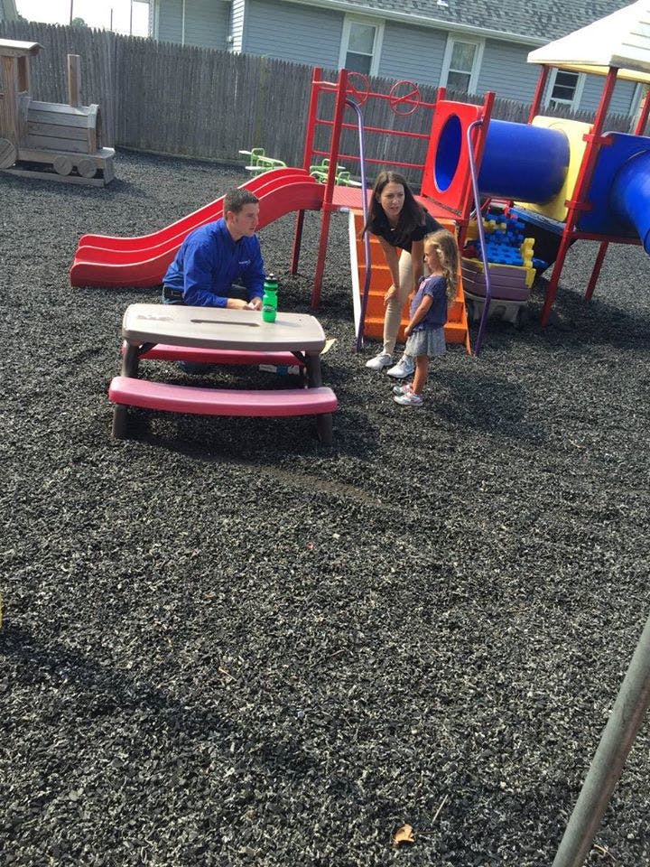 Two adults and a child on a playground with a slide and play structure