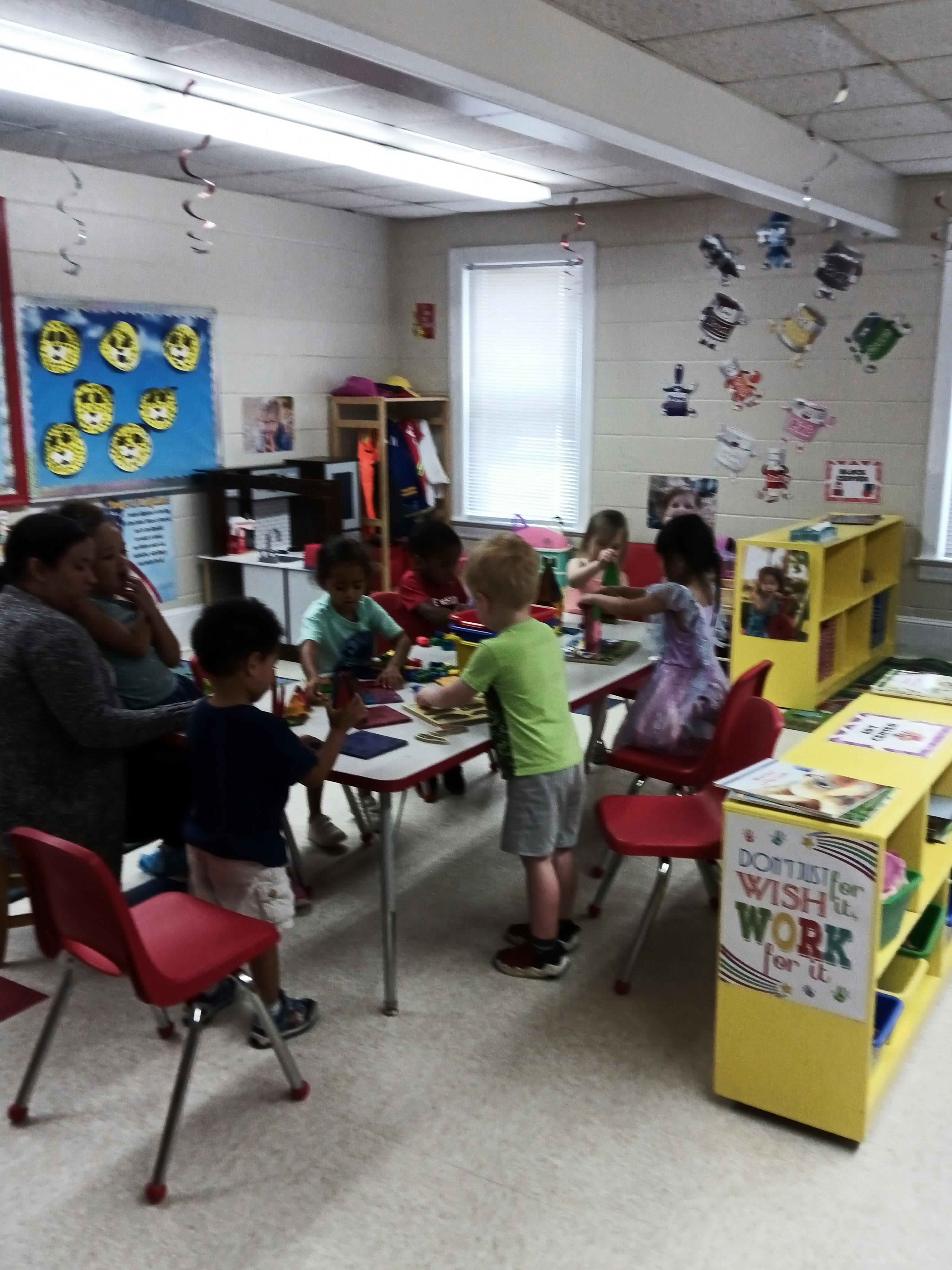 Adult and children at tables in a classroom