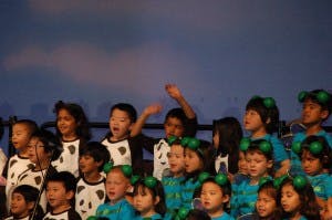 Children on a stage, some wearing headbands