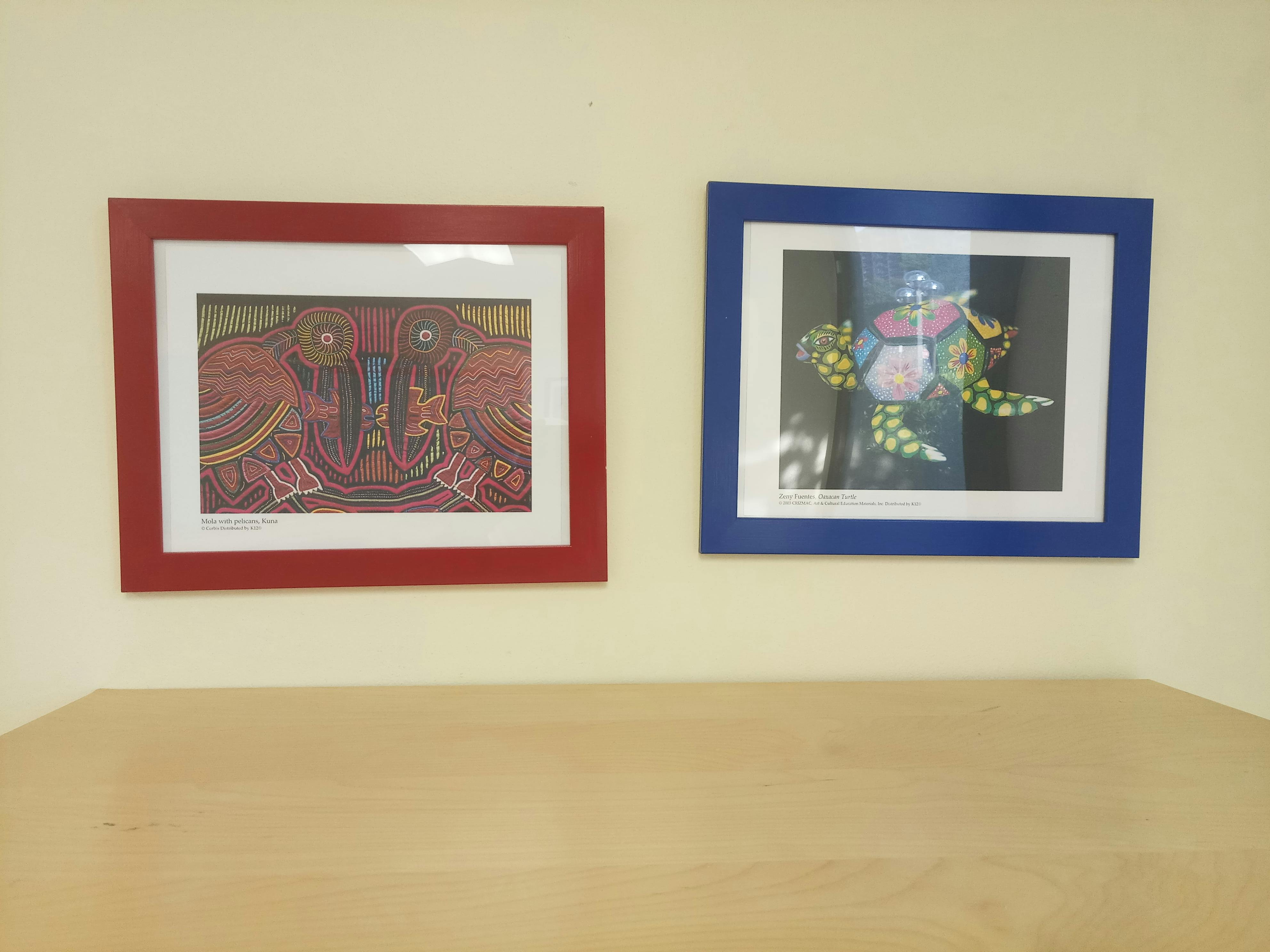 Two framed pictures on a wall, one with abstract art and one with a turtle