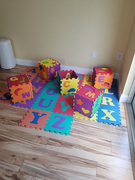 Alphabet play mats and foam blocks on a wooden floor