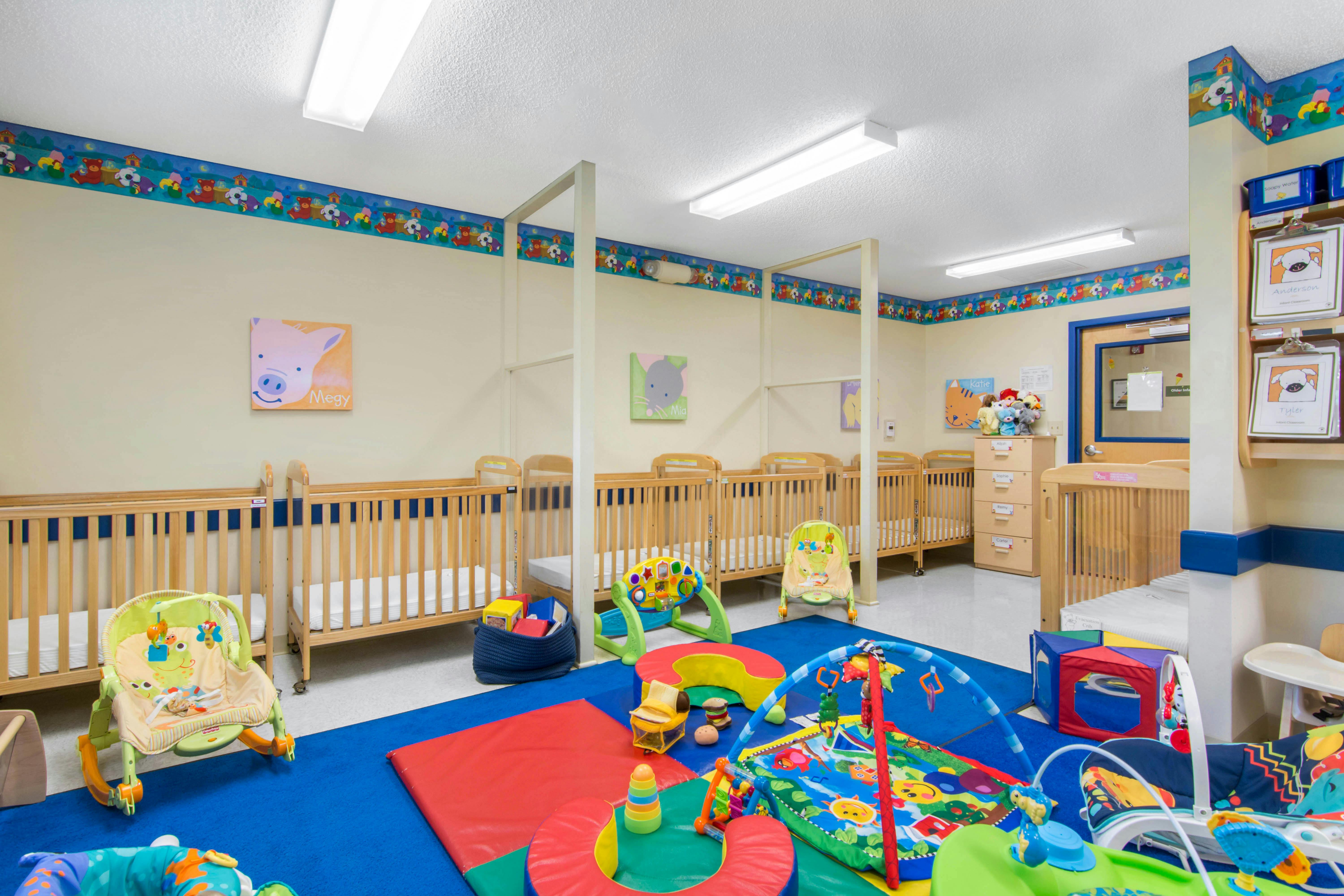 Cribs and play mats in a brightly lit infant classroom