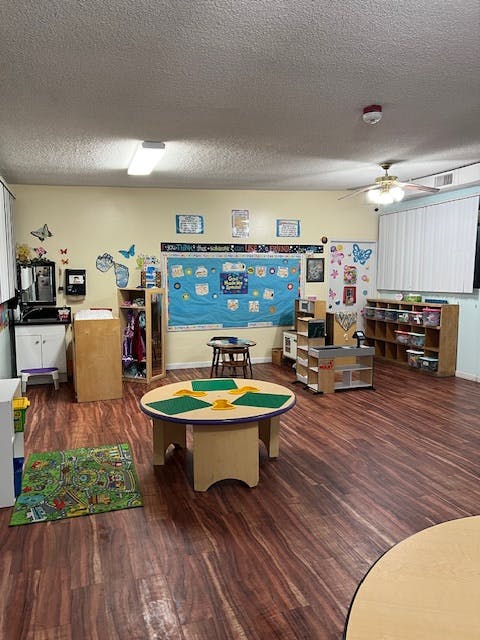 Empty classroom with small tables, chairs, and learning materials