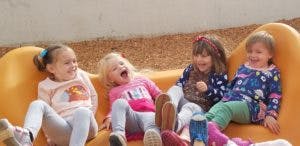Four children sitting on an orange structure