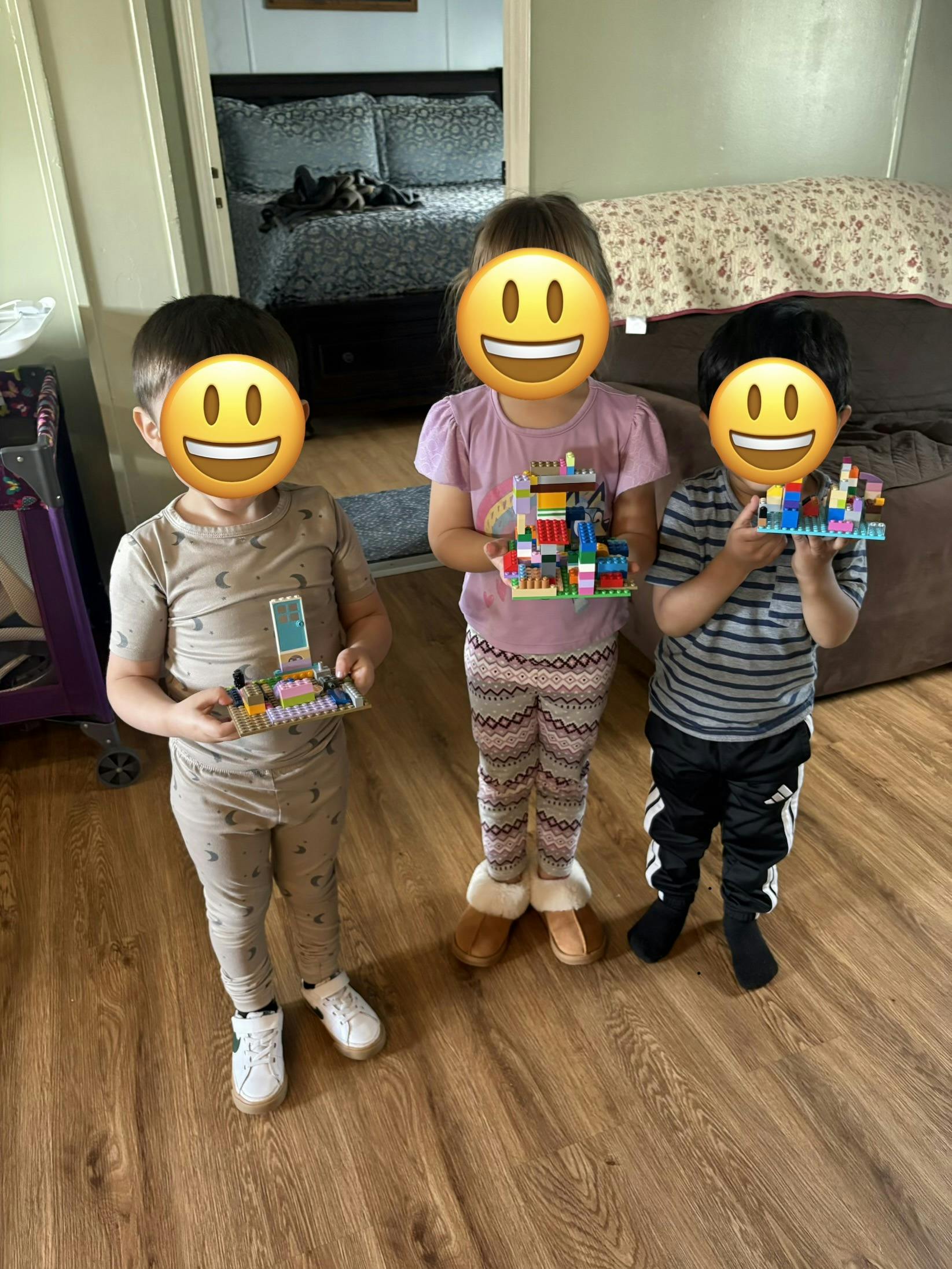 Three children holding their custom plastic building block creations