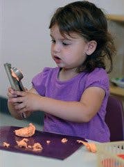 Child playing with modeling clay and a tool