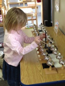 Child playing with bells on a table