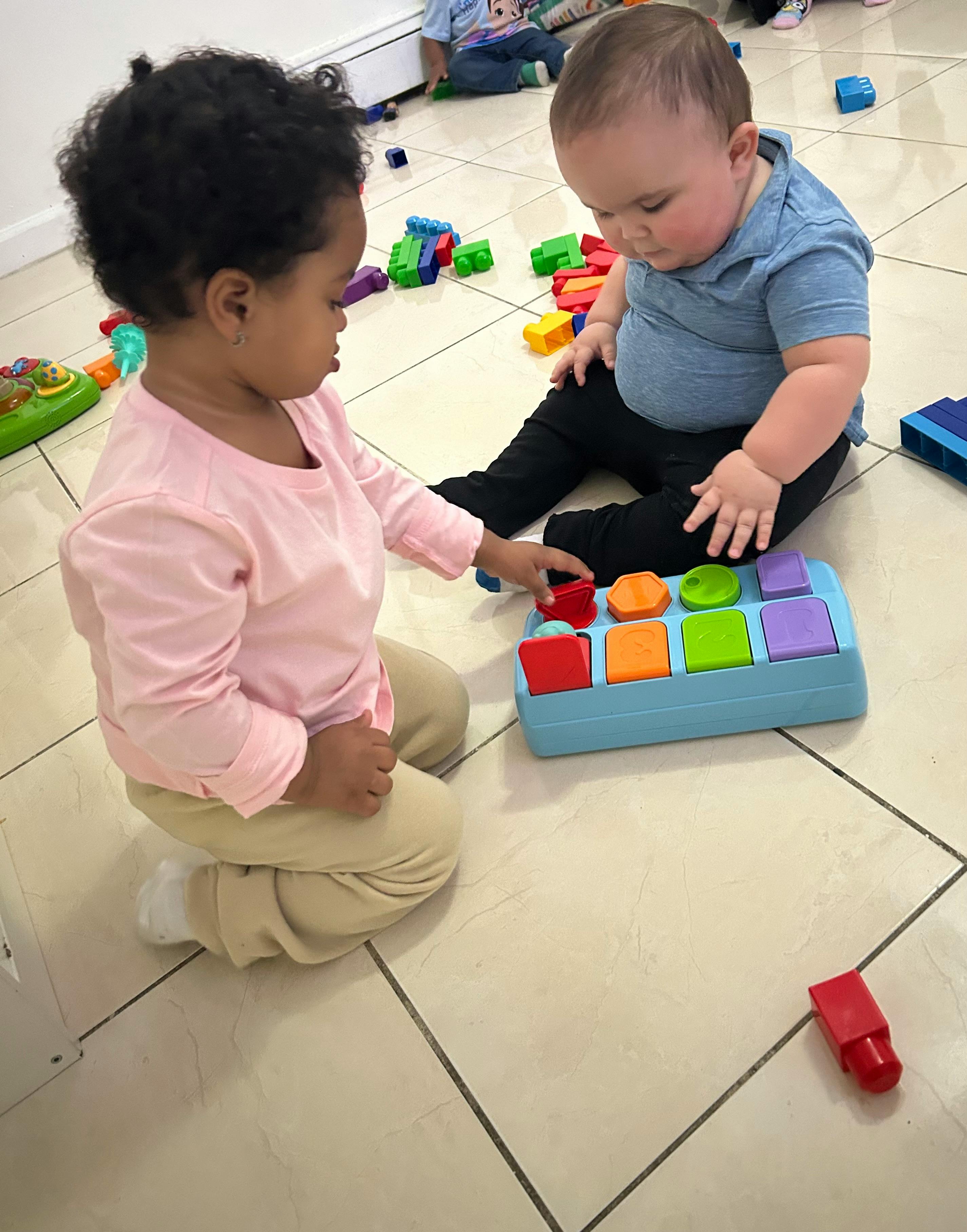 Two children playing with a colorful toy on the floor