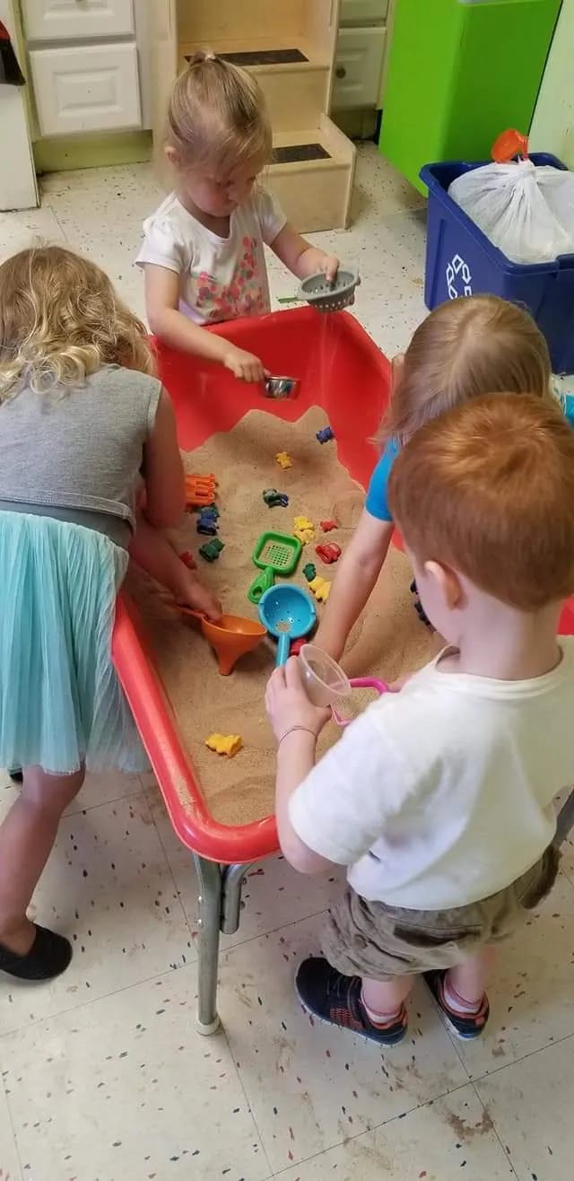 Children playing in a sand table with toys