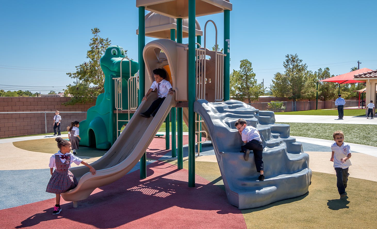 Children playing on a playground structure with slides and climbing structures