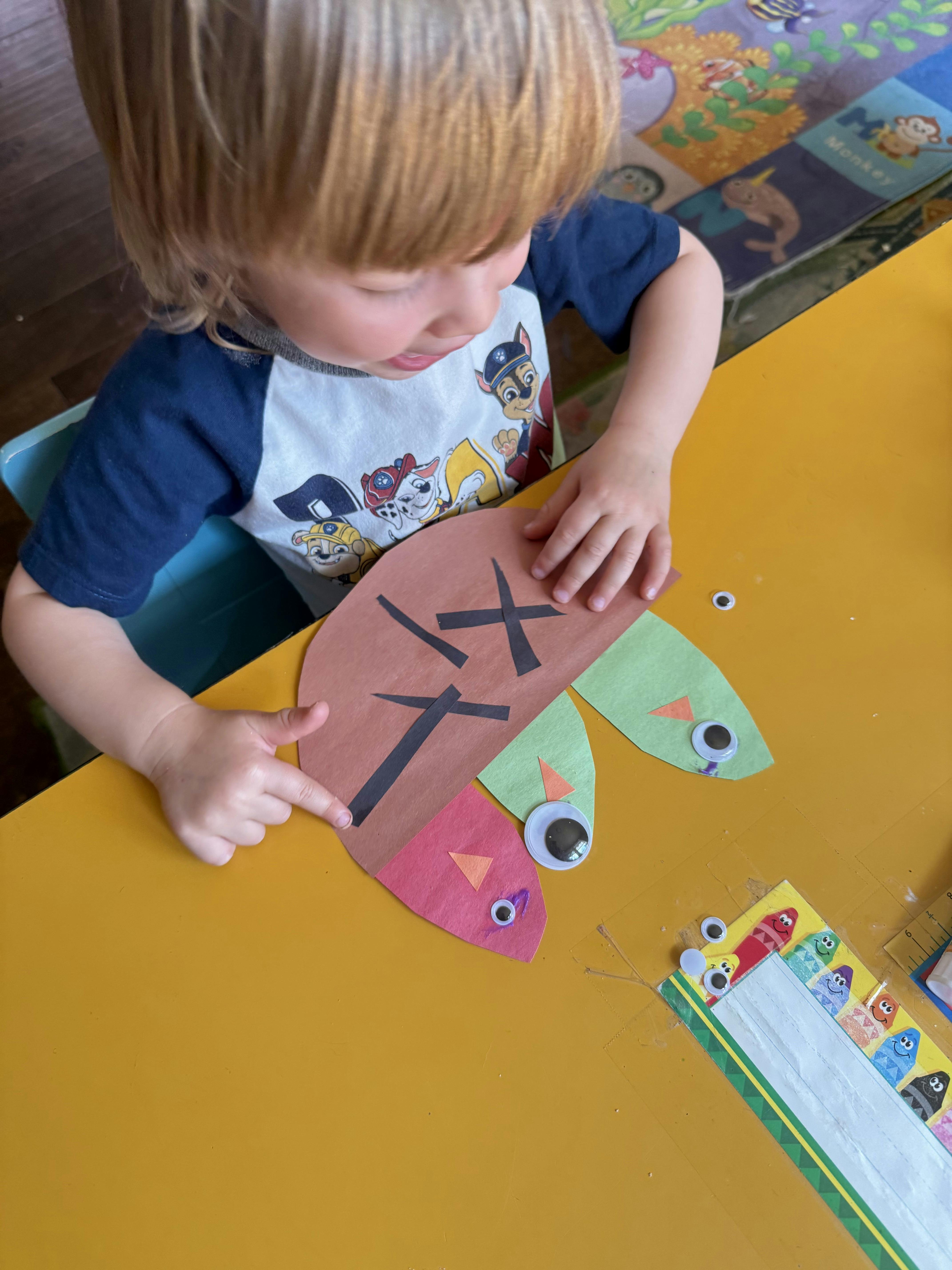 Child making a paper craft with googly eyes