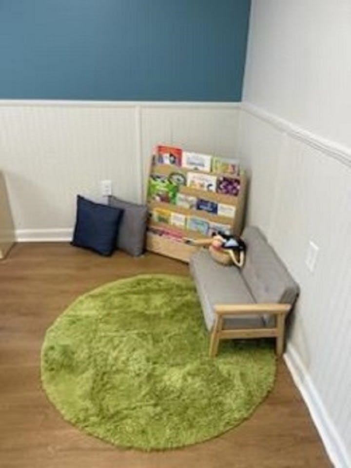 Children's reading nook with a green rug, small couch, and bookshelf