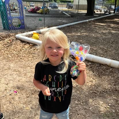 Child holding a bag of colorful toys on a playground