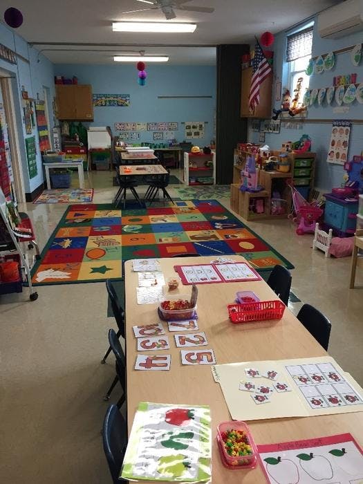 Classroom with tables, chairs, a colorful rug, and learning materials