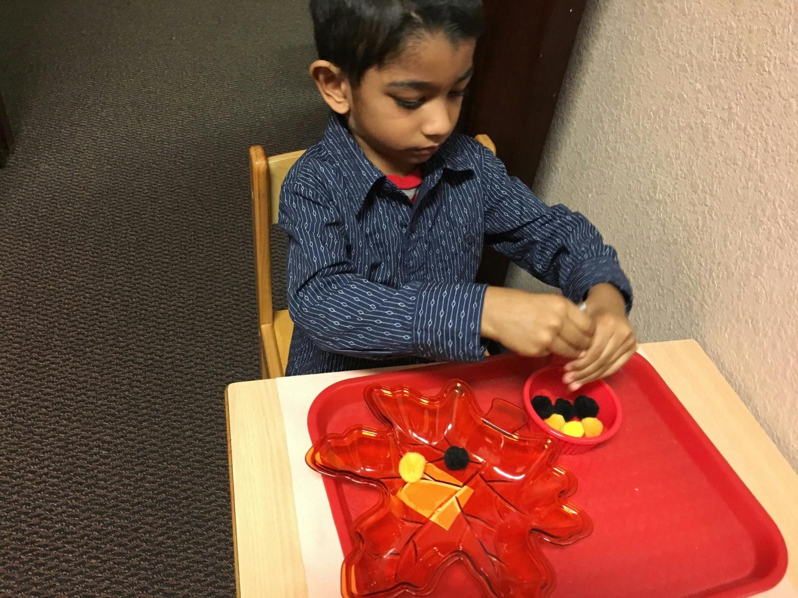 Child playing with small objects on a red tray