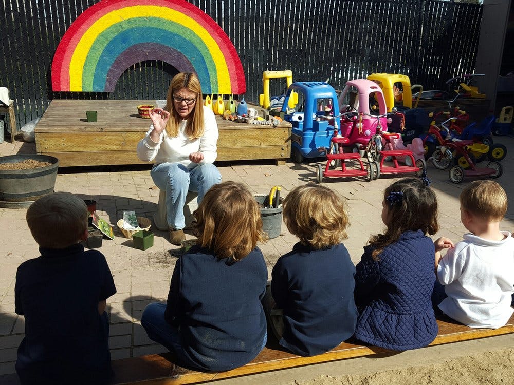 Person speaking to a group of children outdoors