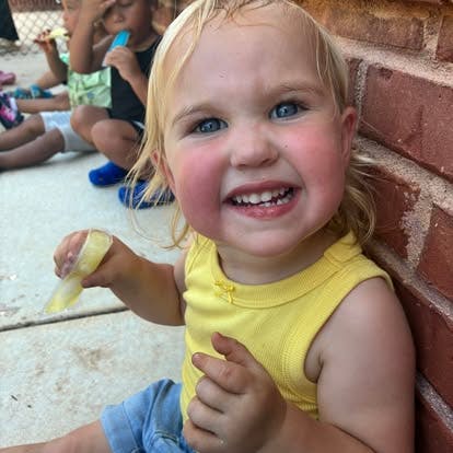Child smiling while holding a popsicle