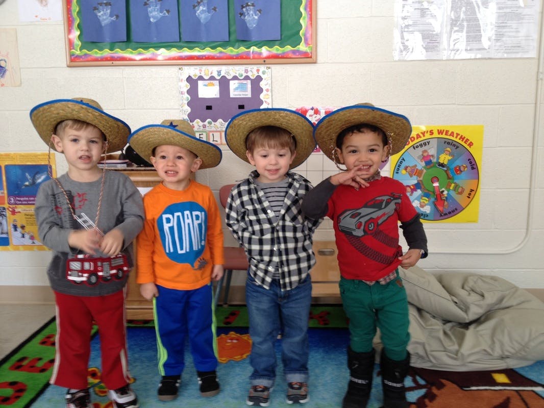 Four children wearing straw hats in a classroom
