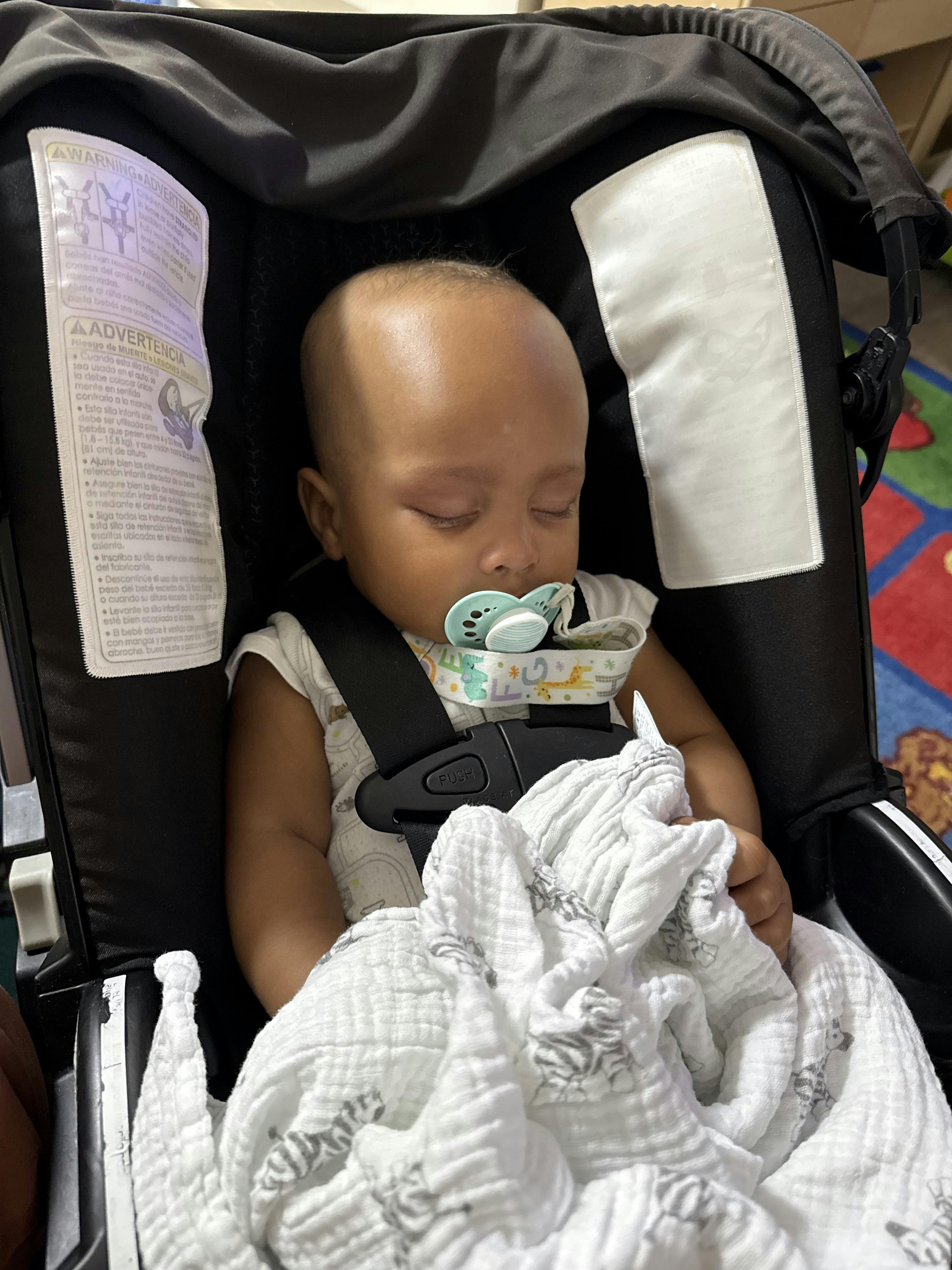 Child sleeping in a car seat with a pacifier