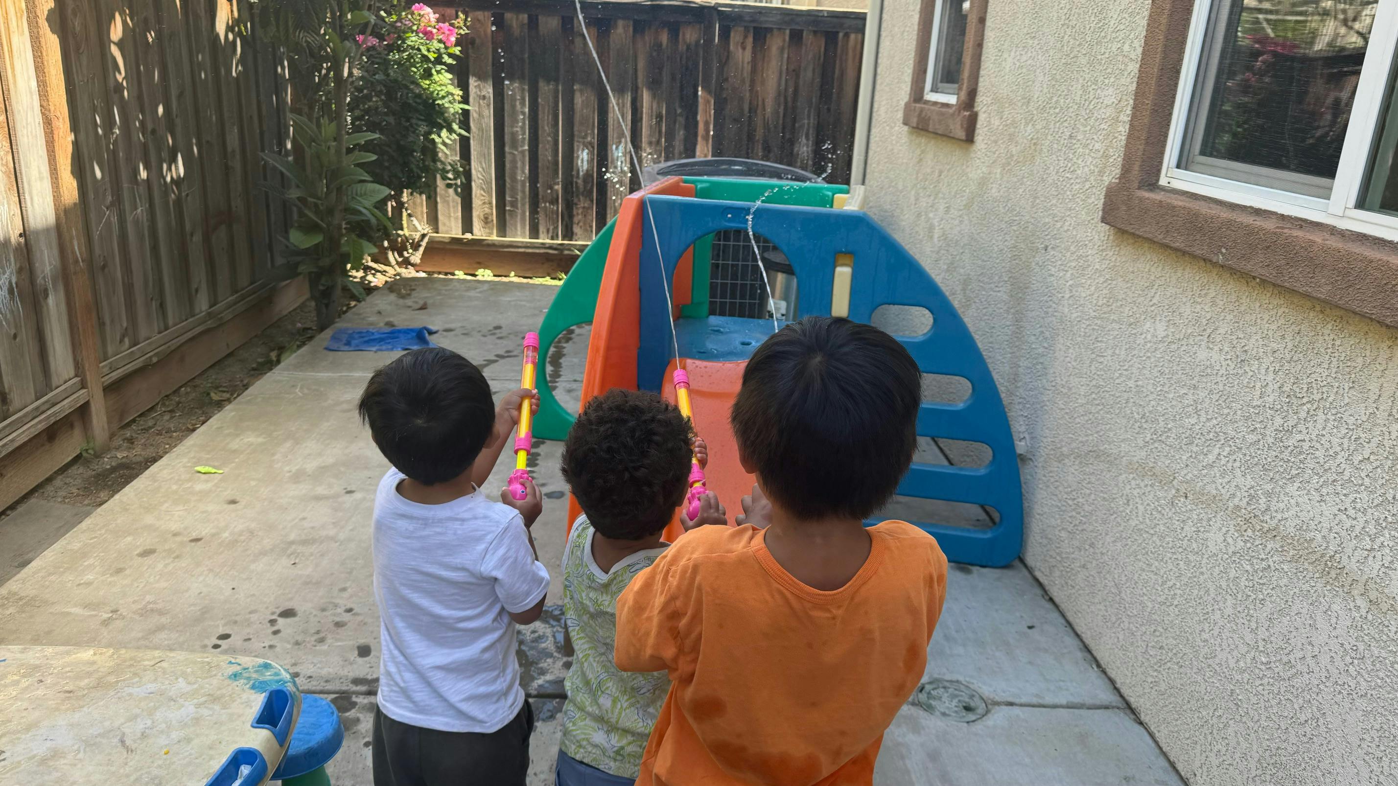 Three children looking at a colorful play structure outdoors